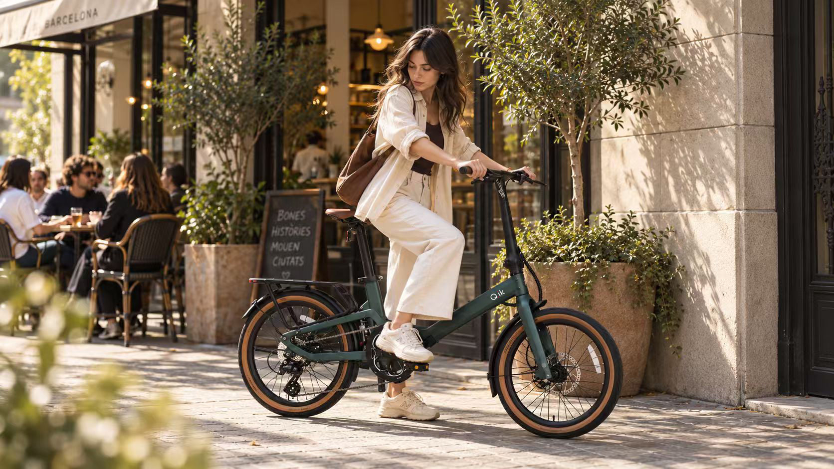 Rider with a Q.ik folding electric bicycle outside a Barcelona cafe